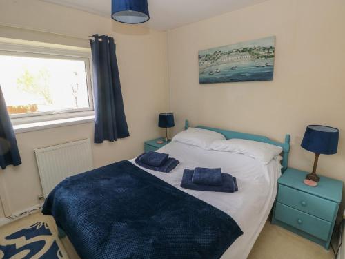 a bedroom with a bed with two blue towels on it at 4 Honeyborough Farm Cottages in Milford Haven