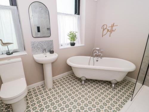a bathroom with a sink and a tub and a toilet at The Keep in Llandudno