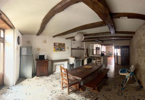une cuisine avec une table en bois et un réfrigérateur dans l'établissement Maison de ville au cœur d'un village de caractère dans le jura, à Saint-Julien