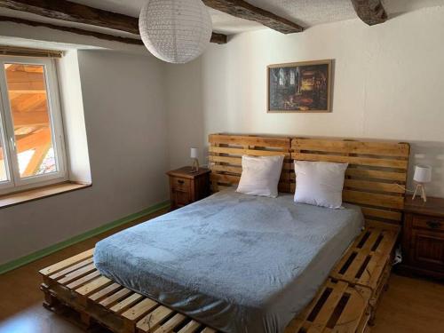 um quarto com uma cama grande e uma cabeceira em madeira em Maison de ville au cœur d'un village de caractère dans le jura em Saint-Julien