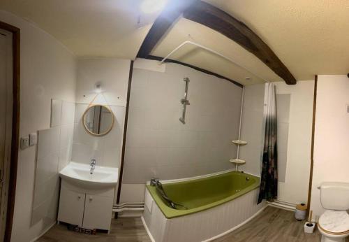 La salle de bains est pourvue d'une baignoire verte et d'un lavabo. dans l'établissement Maison de ville au cœur d'un village de caractère dans le jura, à Saint-Julien