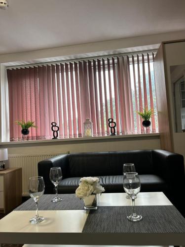 a table with three wine glasses and a couch at Bv Cozy Deighton Studio with Free Parking - Budget-Friendly Stay in Huddersfield