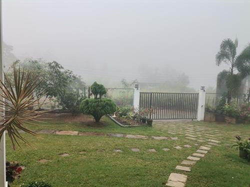 a backyard with a fence and a yard with grass and trees at The Grove in Kandy