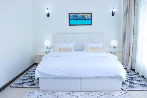 a white bedroom with a large white bed with white sheets at Roseville in Nairobi