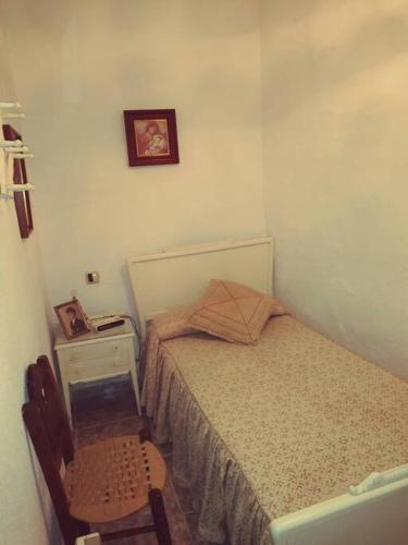 um pequeno quarto com uma cama e uma cadeira em Casa turística en pleno centro de Úbeda em Úbeda
