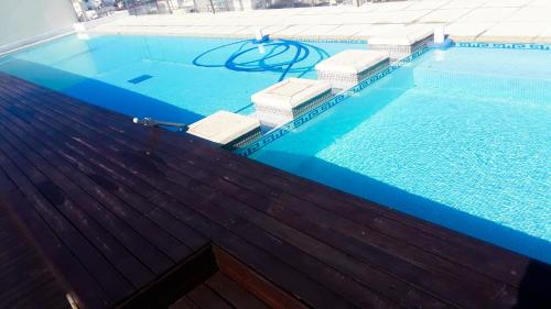 une piscine d'eau bleue et une terrasse en bois dans l'établissement Buenos Aires - Recoleta Luxury Studio con Piscina, Sauna, Gym, Laundry ! Sobre Avenida Santa Fe !, à Buenos Aires