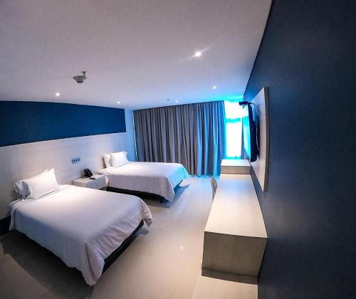 Habitación de hotel con 2 camas y TV en HOTEL MANZUR en Barranquilla