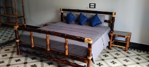 a bedroom with a wooden bed with blue pillows at Mithila Eco Stay - Explore chettinad in Mithilaipatti