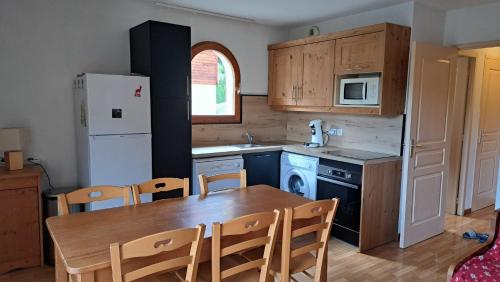 een keuken met een tafel en stoelen en een koelkast bij Les granges d'Arvieux 701 in Arvieux