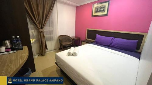 a bedroom with a bed and a pink wall at Hotel Grand Palace Ampang in Ampang