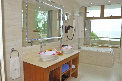 a bathroom with two sinks and a large mirror at Crown Beach Hotel Seychelles in Pointe Au Sel 