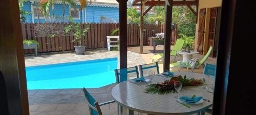 a table and chairs next to a swimming pool at Villa bel in Sainte-Anne