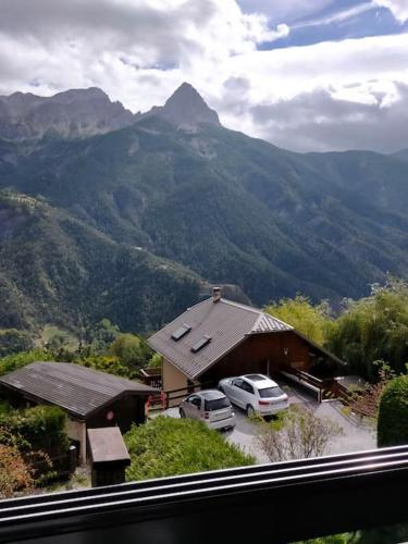 een huis met twee auto's geparkeerd voor een berg bij location studio vacances ou weekend Pra Loup résidence La Croix Haute in Uvernet