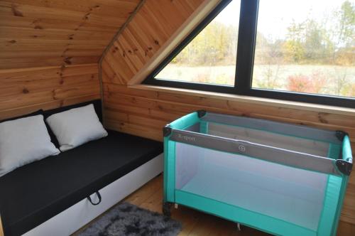 um pequeno quarto com uma cama e uma janela em Luksusowe domki Mazury em Mrągowo