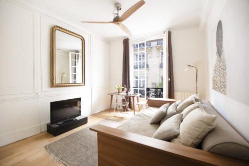 un salon avec un canapé et un miroir dans l'établissement GuestReady - Charmant studio à 10 mins du Louvre, à Paris