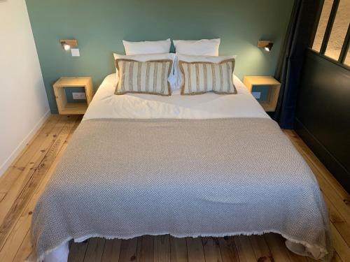 a bedroom with a large bed with white sheets and pillows at La Maison des Ecureuils - Bruniquel in Bruniquel