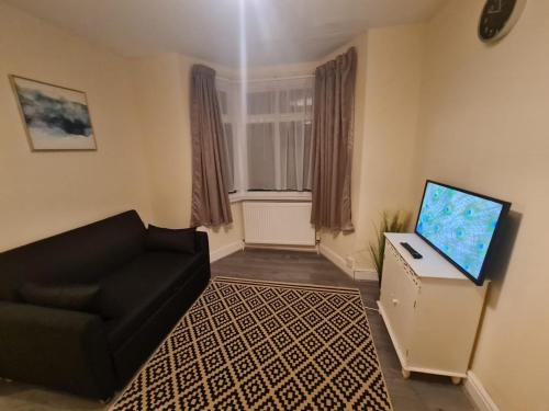 a living room with a couch and a flat screen tv at One Bedroom Apartment with Garden in London