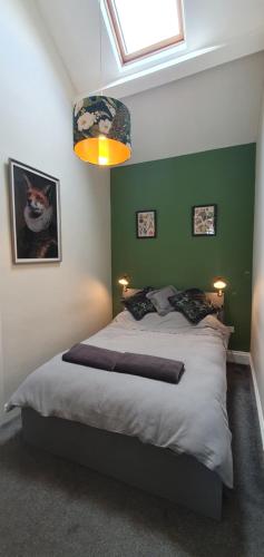 um quarto com uma cama grande e uma parede verde em Spring Cottage at Pen Y Coed Hall em Dolgellau