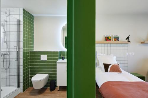 - une salle de bains verte et blanche avec un lit et une douche dans l'établissement Hife Toulouse Labège, à Labège