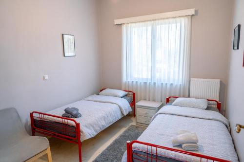 two beds in a small room with a window at Filoxenia House at Anemochori village in Pyrgos