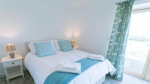 a bedroom with a white bed with blue pillows and a window at Hebog in Llanrhwydrys