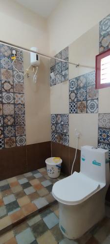 a bathroom with a toilet and tiles on the wall at Mithila Eco Stay - Explore chettinad in Mithilaipatti