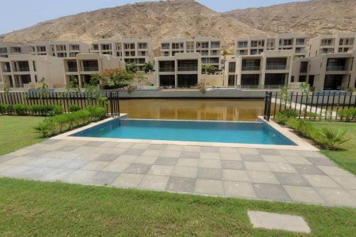 a swimming pool in front of a building at muscat bay nameer villa in Muscat