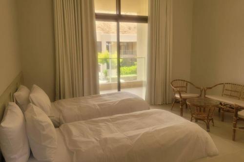 a bedroom with two beds and a table and a window at muscat bay nameer villa in Muscat