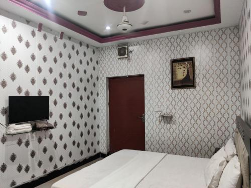 a bedroom with a bed and a tv on a wall at Hotel New Star View in Bahawalpur