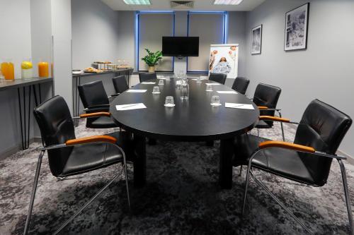 a conference room with a black table and chairs at Mercure Warszawa Grand in Warsaw