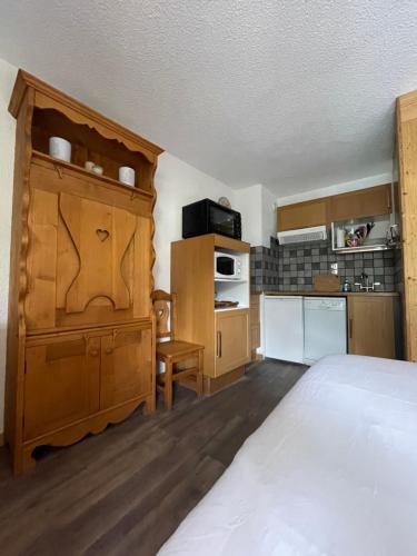 a bedroom with a large bed and a kitchen at Superbe studio au pied des oeufs in Champagny-en-Vanoise