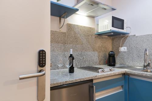 a small kitchen with blue cabinets and a sink at Roisa Centro in Madrid