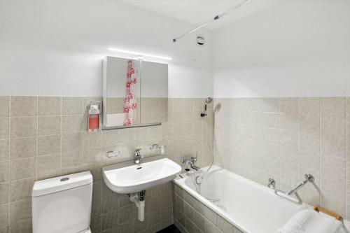 een badkamer met een wastafel, een toilet en een bad bij Geräumige Ferienwohnung in ruhiger Lage in Sennwald