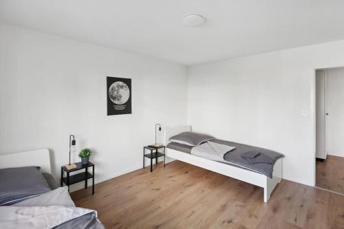 a white bedroom with two beds and a wooden floor at Geräumige Ferienwohnung in ruhiger Lage in Sennwald
