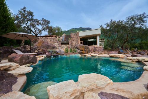 a swimming pool with rocks in a backyard at CASA RAIZ Handmade House Luxury Stay in Calca