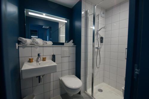 y baño con aseo, lavabo y ducha. en ibis budget Loudéac Vélodrome, en Loudéac