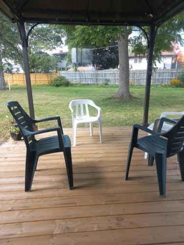 drie stoelen en een tafel op een houten terras bij Sunshine Bayridge in Kingston