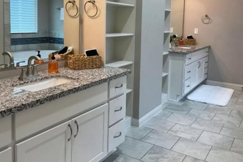 a bathroom with white cabinets and a sink and a tub at Relaxing Retreat Early check in & late check out in Houston