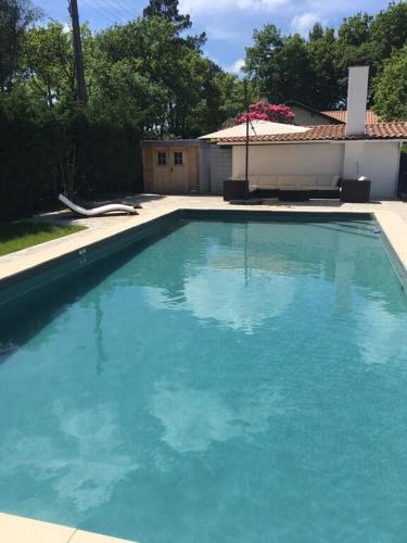 une grande piscine bleue devant une maison dans l'établissement Villa familiale piscine-Océan & Bassin d'Arcachon, à Le Porge