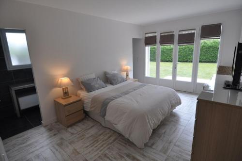 - une chambre blanche avec un grand lit et des fenêtres dans l'établissement Villa familiale piscine-Océan & Bassin d'Arcachon, à Le Porge