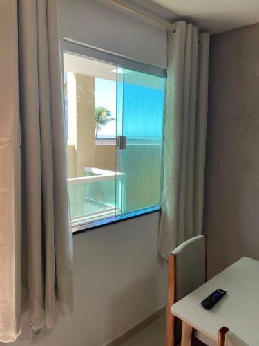 una finestra in una stanza con tavolo e tavolo e un tavolo di Apartamento 1 quarto Zona Sul Praia a Ilhéus