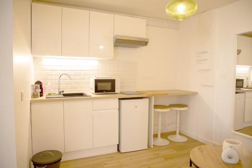 uma cozinha branca com um lavatório e um frigorífico em Le Marais - Appart'Escale em Saint-Nazaire