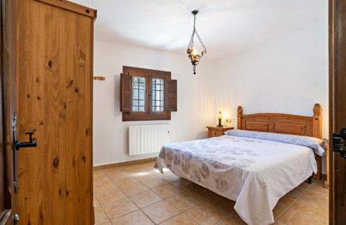 1 dormitorio con 1 cama y puerta de madera en Molino del Nacimiento, en Laujar de Andarax
