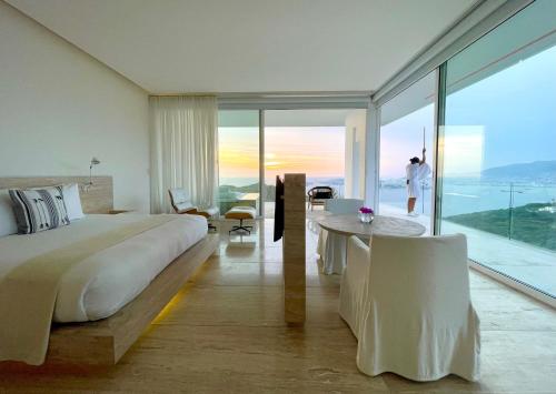 a bedroom with a bed and a table and a view at Encanto Acapulco in Acapulco