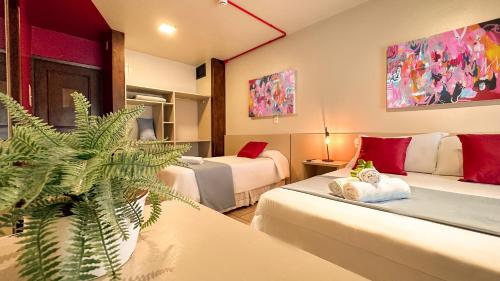 una habitación de hotel con 2 camas y una planta en Luzzy Hotel en Canela