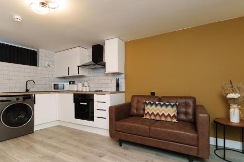 a living room with a couch and a kitchen at The Oasis Apartment in Leeds