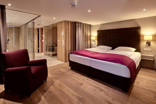 a bedroom with a large bed and a chair at Staufen Chalets am Kalvarienberg in Oberstaufen