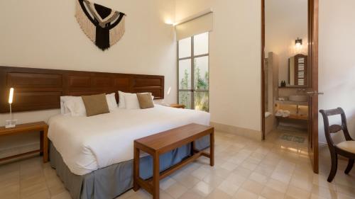 a bedroom with a large white bed and a table at Villa Orquídea Boutique Hotel in Mérida