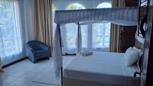 um quarto com uma cama, uma cadeira e janelas em Crystal beach apartment em Mombasa