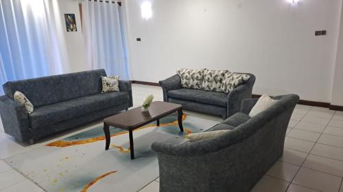 uma sala de estar com três sofás e uma mesa de centro em Crystal beach apartment em Mombasa